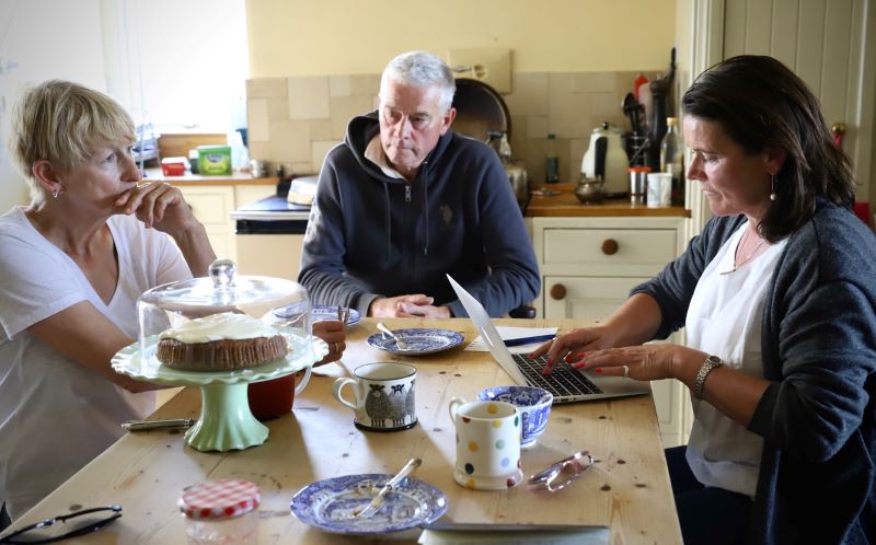 Three people sat having discussion around kitchen table