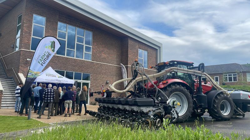 Tractor with cultivator next to crowd of people and banners